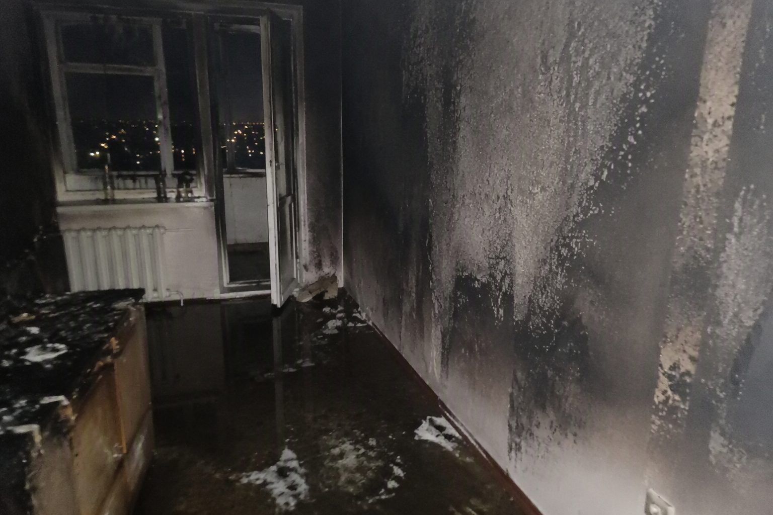 Комната после тушения пожара: копоть на стенах и вода на полу — фото с телефона